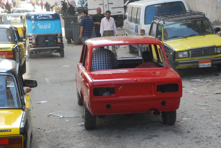 Frisch rot gespritzte Fiatkarrosserie ohne Fenster und Lichter auf eigenen Rädern unterwegs in Alexandria