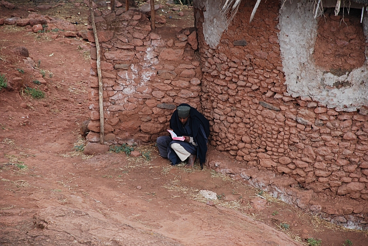 Ein Orthodoxer Priester in Lalibela studiert draussen kauernd die Schriften