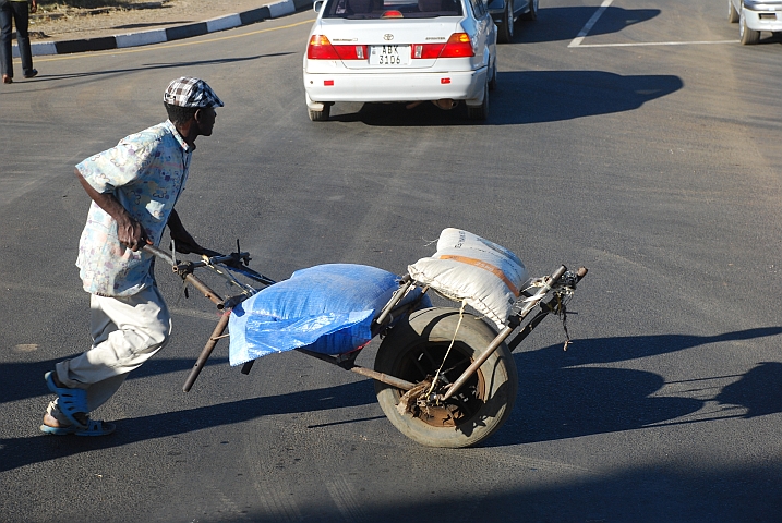 Mann mit seiner selbstgebastelten Transportschubkarre unterwegs im Stadtverkehr von Kabwe