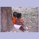 Zwei kleine Kinder sitzen unter einem Mangobaum