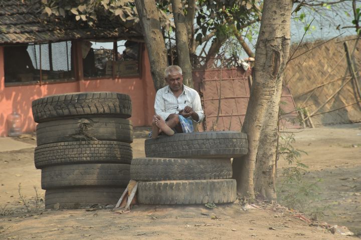 Älterer Mann sitzt gemütlich auf einem Reifenstapel in der Nähe von Kolkata