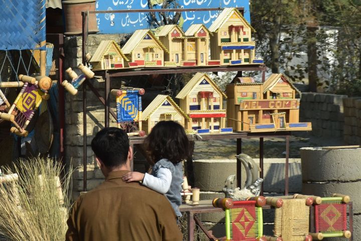 Mädchen auf dem Arm ihres Vaters vor Spielzeughäusern aus Holz