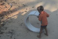Kleiner Junge spielt mit einer Betonröhre