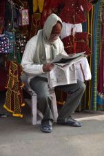 Händler liest vor seinem Laden die Zeitung