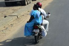 Hübsch gekleidete Frau im Damensitz auf einem Motorrad-Taxi