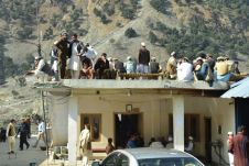 Versammlung von Männern in, um und auf dem Flachdach eines Hauses in Dassu