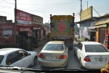 Drei Autos drängeln nebeneinander auf einer Strasse mit Gegenverkehr in Taxila