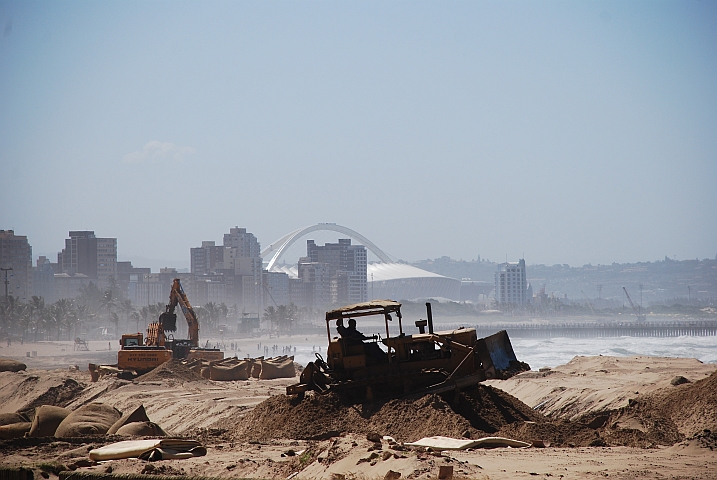 Schwere Maschinen beackern den Strand der goldenen Meile von Durban, die f&uuml;r die Fussball-WM 2010 (im Hintergrund das neue Stadion) in Schuss gebracht wird